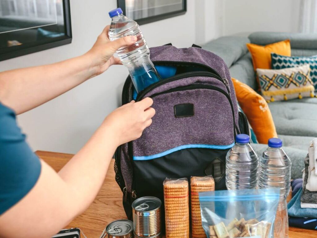 Packing an emergency kit with water and food supplies to support whole home generator readiness during summer storms.